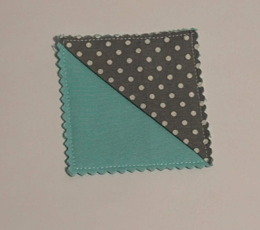Fabric sample with gray polka dot pattern and teal solid color on a beige background